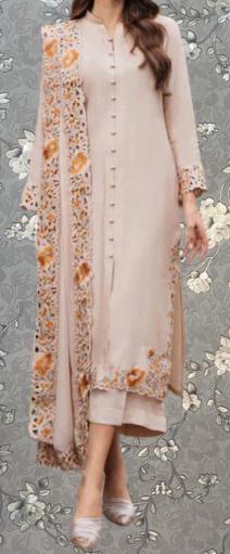 A woman wearing a long, light pink dress with intricate floral embroidery on the sleeves and hem.