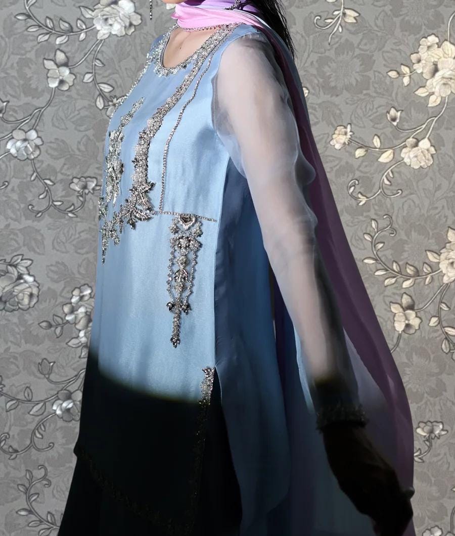 A woman wearing a blue dress with intricate embroidery and a long purple scarf.