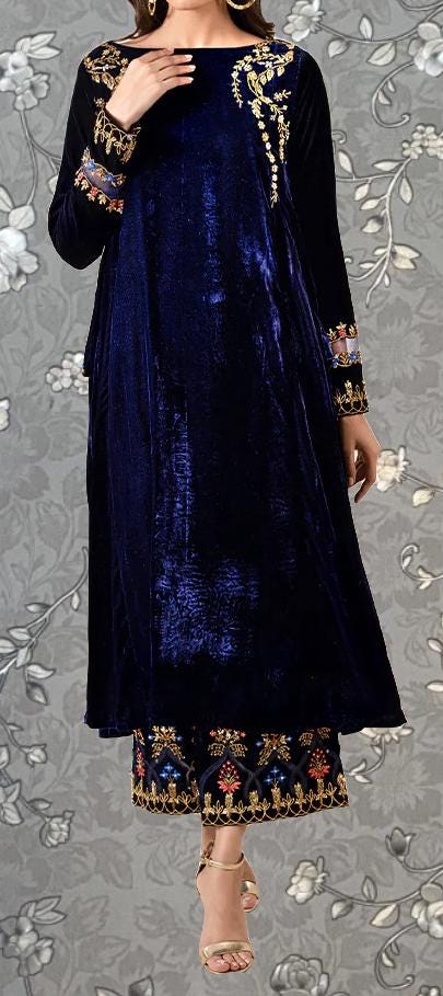 A woman wearing a long, navy blue velvet dress with gold embroidery and a matching skirt.