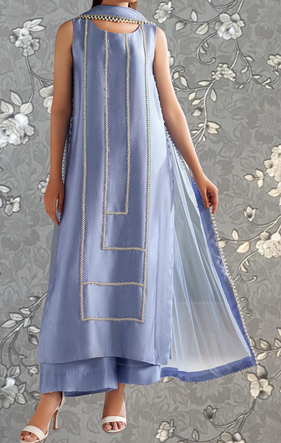 A woman wearing a long, sleeveless dress with a geometric pattern and a sheer overlay.