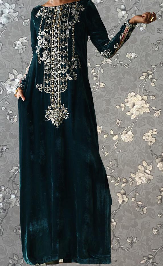 A woman wearing a long, dark green velvet dress with intricate embroidered patterns on the bodice and sleeves.