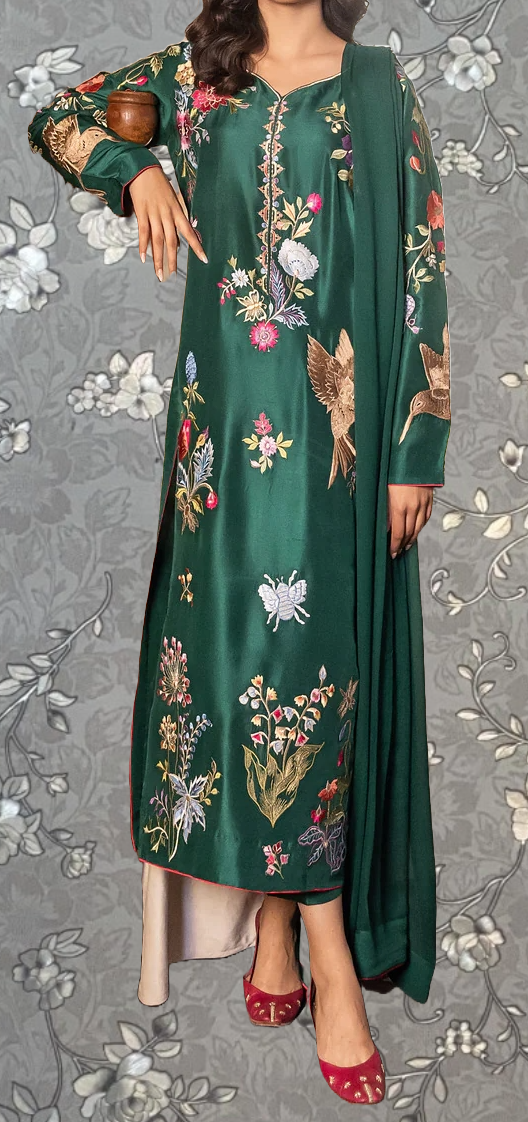 A woman wearing a long green dress with floral embroidery and a matching green shawl.