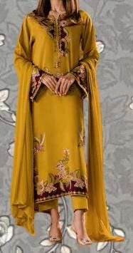 A woman wearing a yellow dress with floral embroidery and a matching shawl.