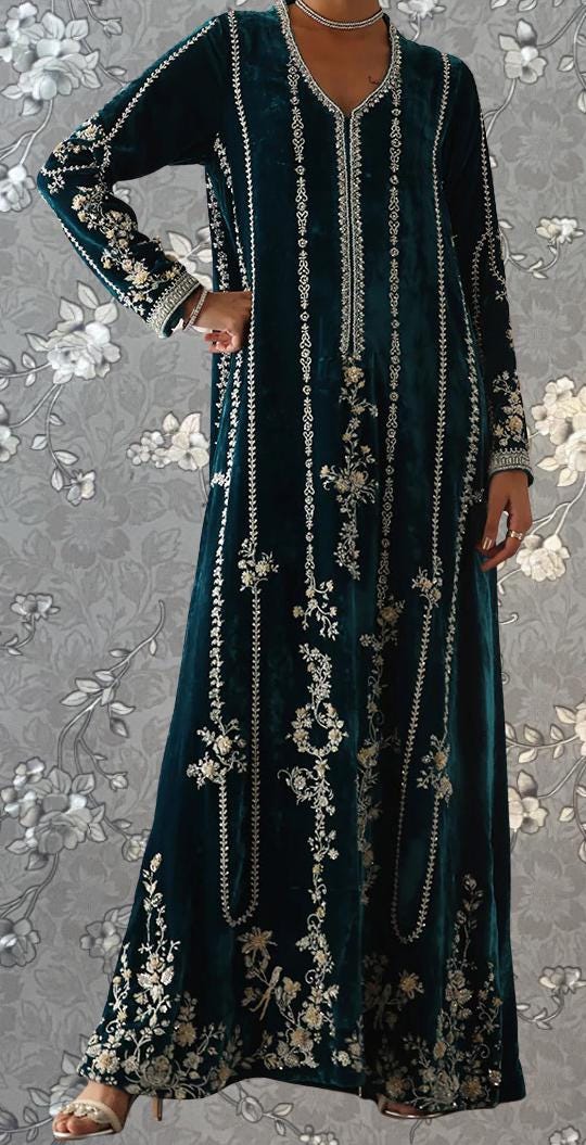 A woman wearing a long, dark green dress with intricate embroidered patterns.