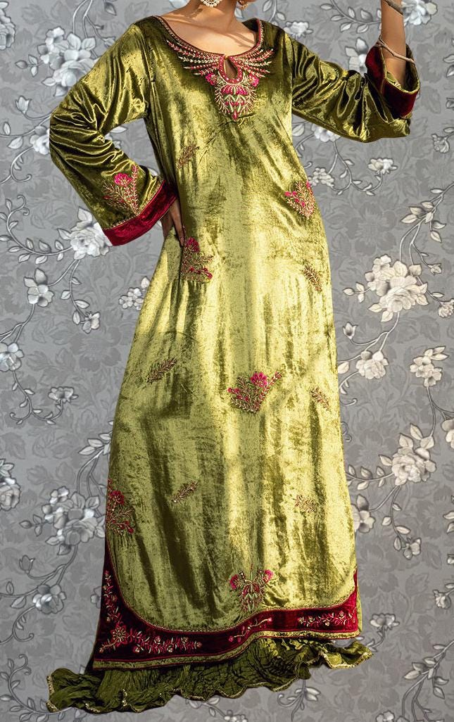 A woman wearing a long, green velvet dress with red accents and floral embroidery.