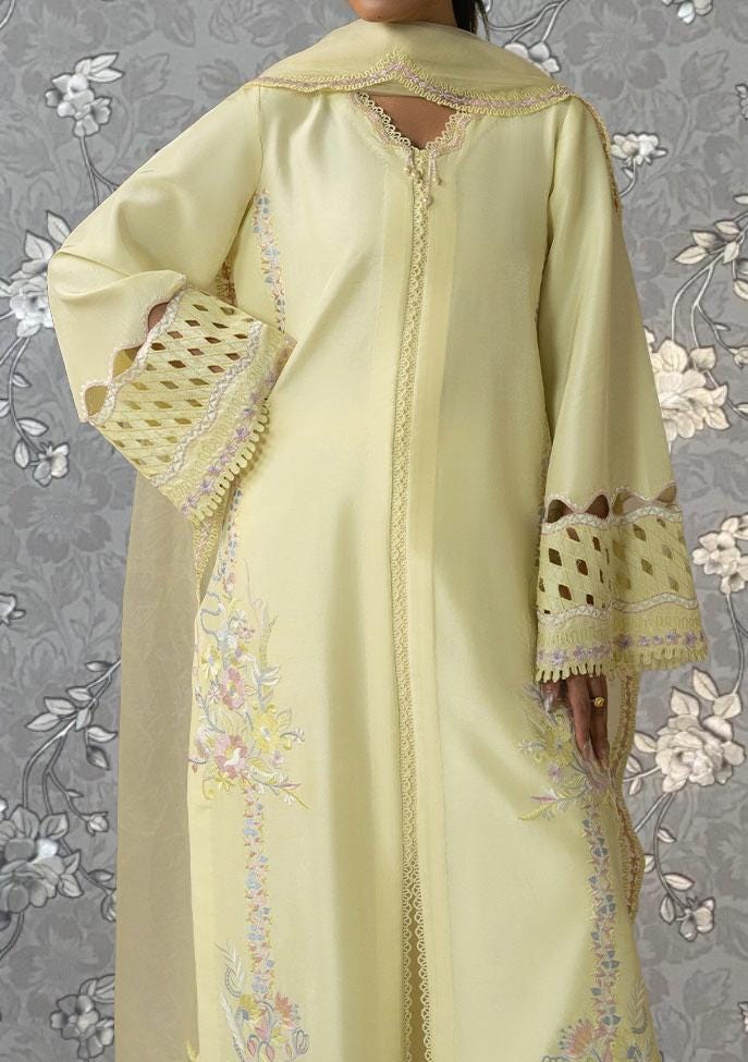 A person wearing a long, yellow dress with intricate embroidered patterns and lace trim.