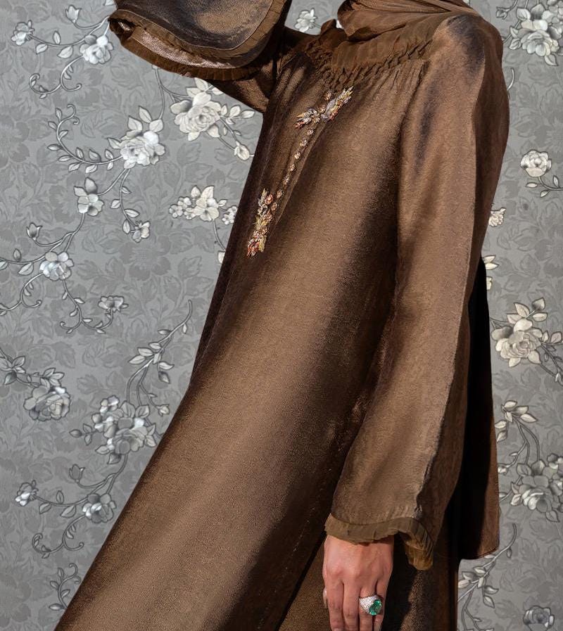 A close-up of a brown dress with a floral pattern on the background.