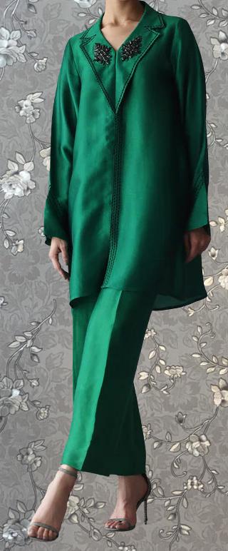 A person wearing a green dress with a floral pattern and a matching green jacket with a floral design on the collar.