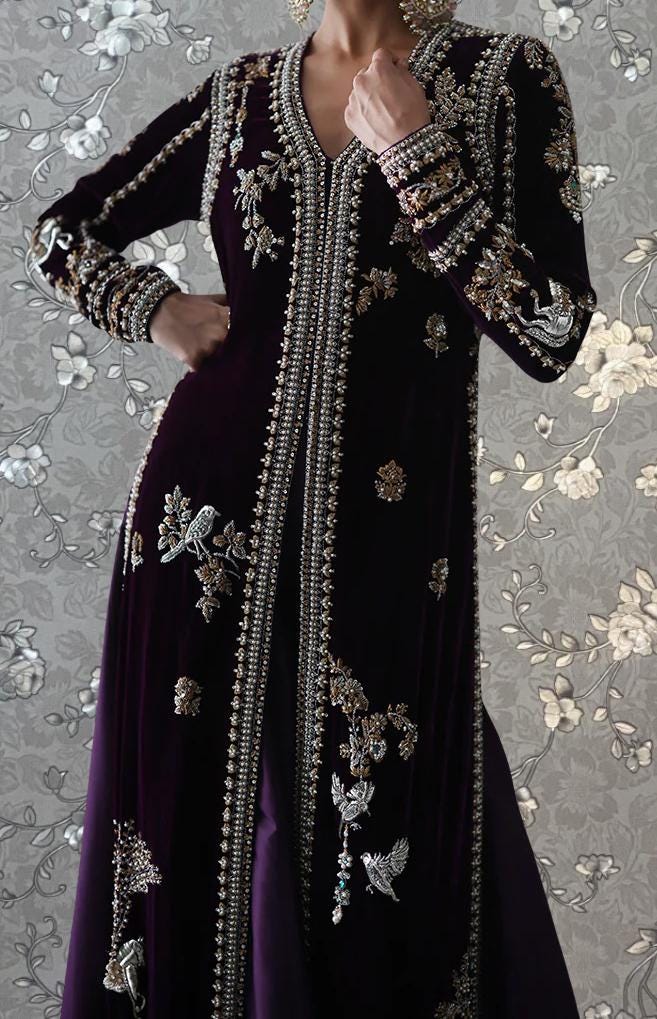 A woman wearing an ornate, purple velvet dress with intricate embroidery and embellishments.