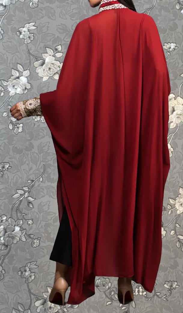 A person wearing a long red cape with a floral pattern on the back.
