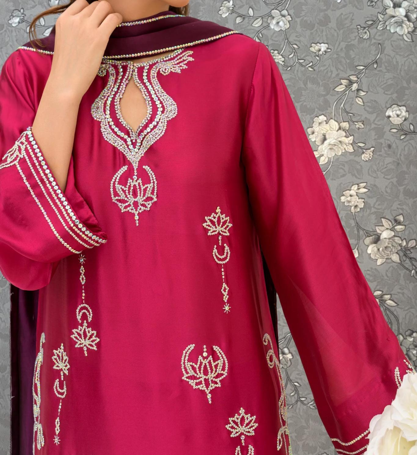 A close-up of a person wearing a vibrant red dress with intricate embroidered designs.