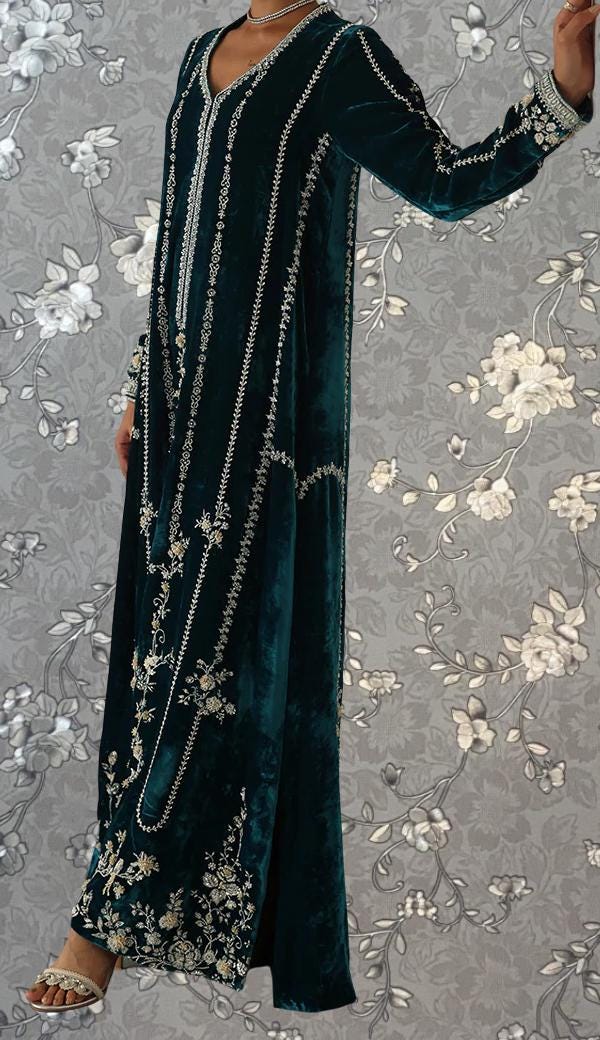 A woman wearing a long, green velvet dress with intricate embroidered patterns and designs.