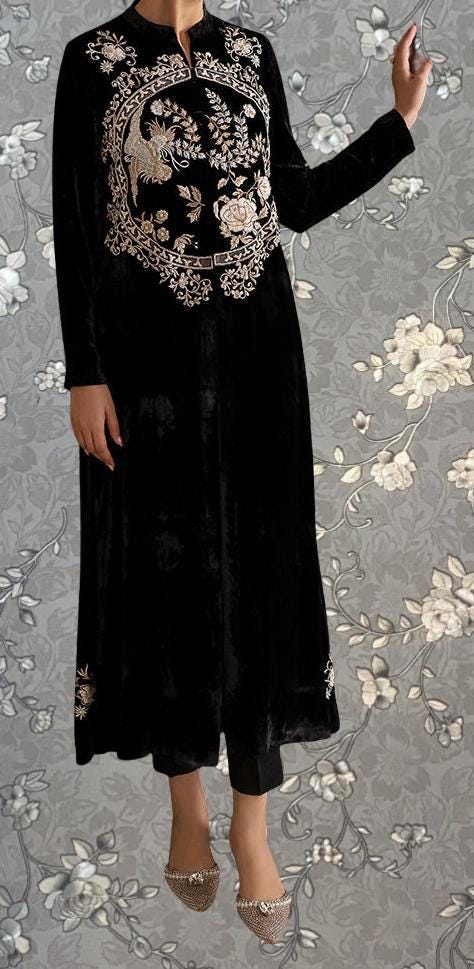 A person wearing a long black dress with intricate embroidered designs on the front.