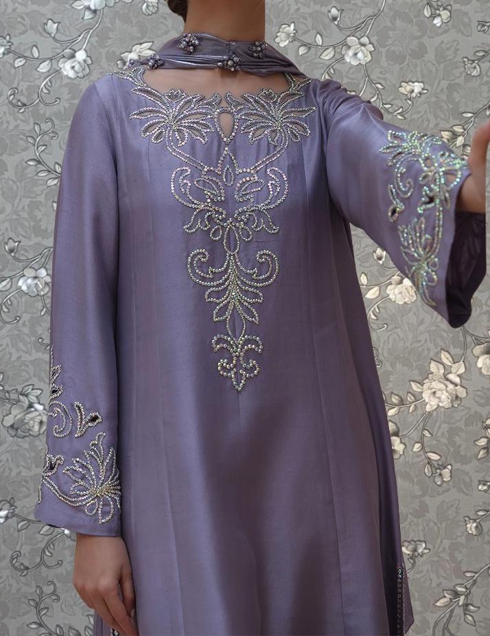A person wearing a purple dress with intricate embroidered designs on the front.