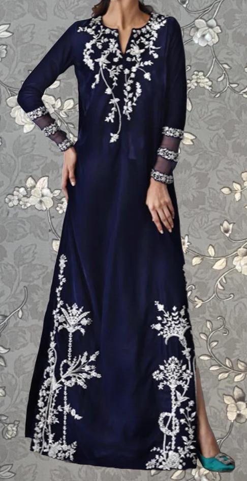 A woman wearing a long navy blue dress with white floral embroidery on the bodice and sleeves.