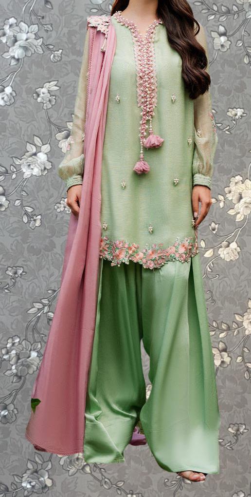 A woman wearing a green and pink dress with floral embroidery and a pink shawl.
