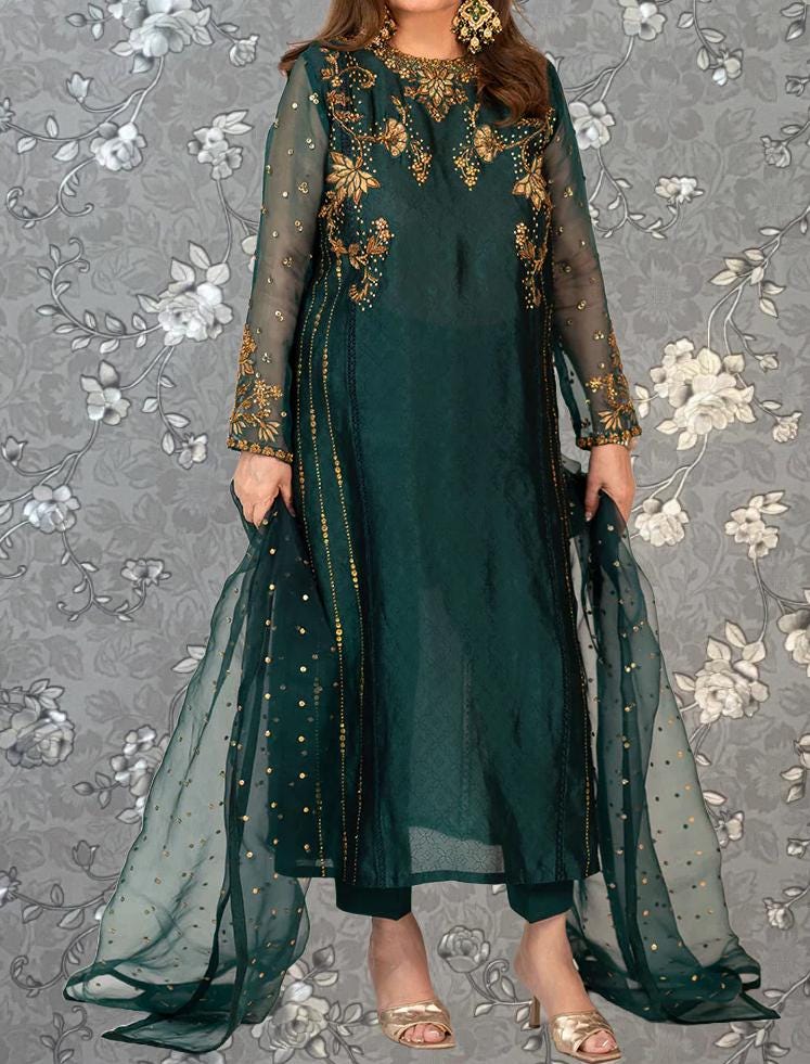 A woman wearing a long, green dress with gold embroidery and a sheer green and gold shawl.