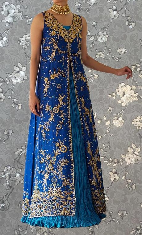A woman wearing a long, blue dress with gold embroidery and a matching gold choker necklace.