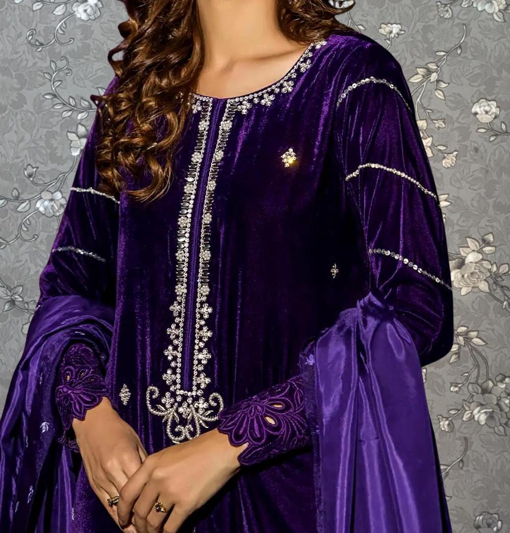 A woman wearing a purple velvet dress with intricate embroidery and a gold brooch on the chest.