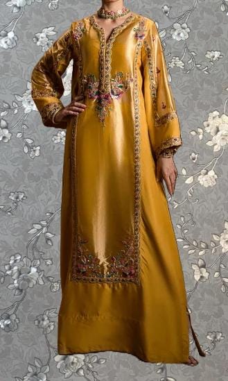 A woman wearing a long, gold dress with intricate embroidery and floral patterns.