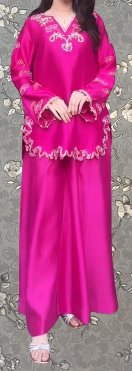 A woman wearing a long pink dress with intricate embroidery and a high collar.