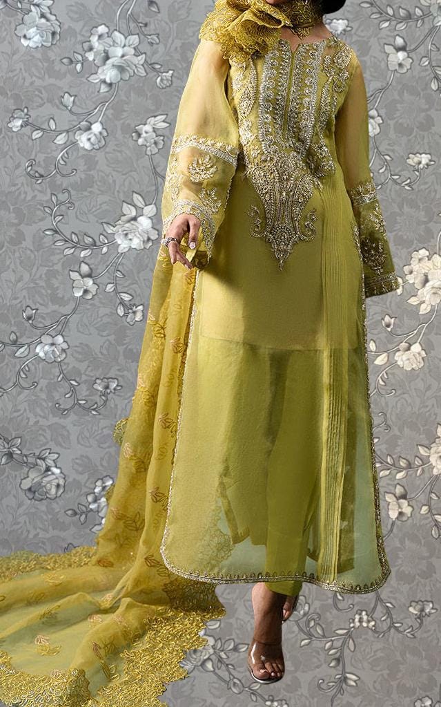 A woman wearing a long, yellow dress with intricate gold embroidery and a matching yellow shawl.