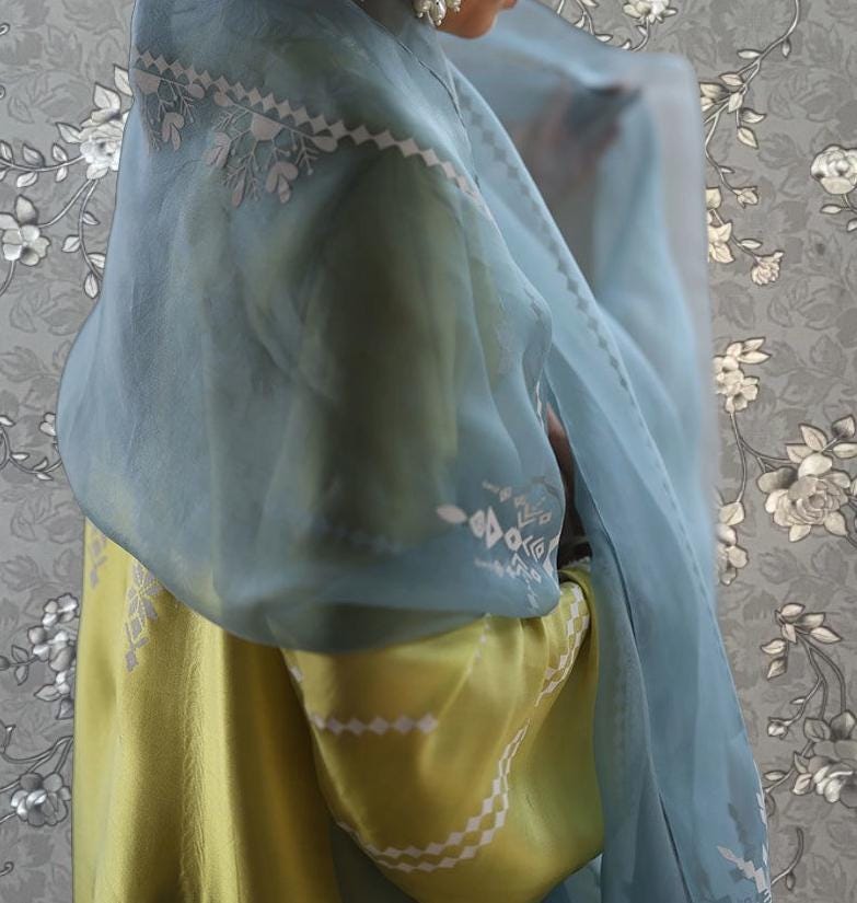 a person wearing a blue and yellow dress with a matching blue shawl draped over their shoulders.