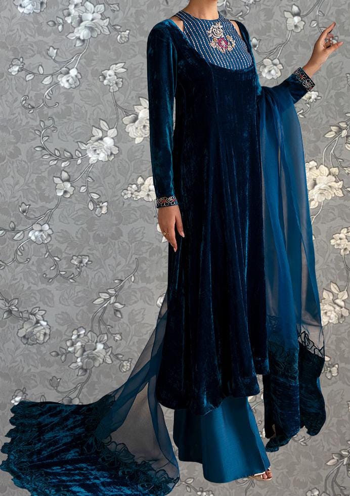 A woman wearing a long, blue velvet dress with a matching blue shawl draped over her shoulders.