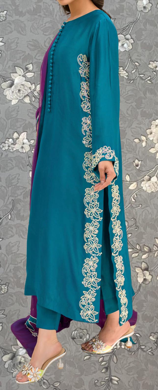 A woman wearing a teal blue dress with white floral embroidery on the sleeves and pants, paired with silver heels.