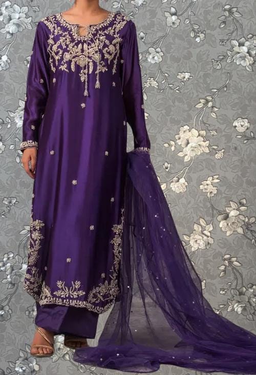 A person wearing a long purple dress with intricate embroidery and a matching purple shawl draped over their shoulders.