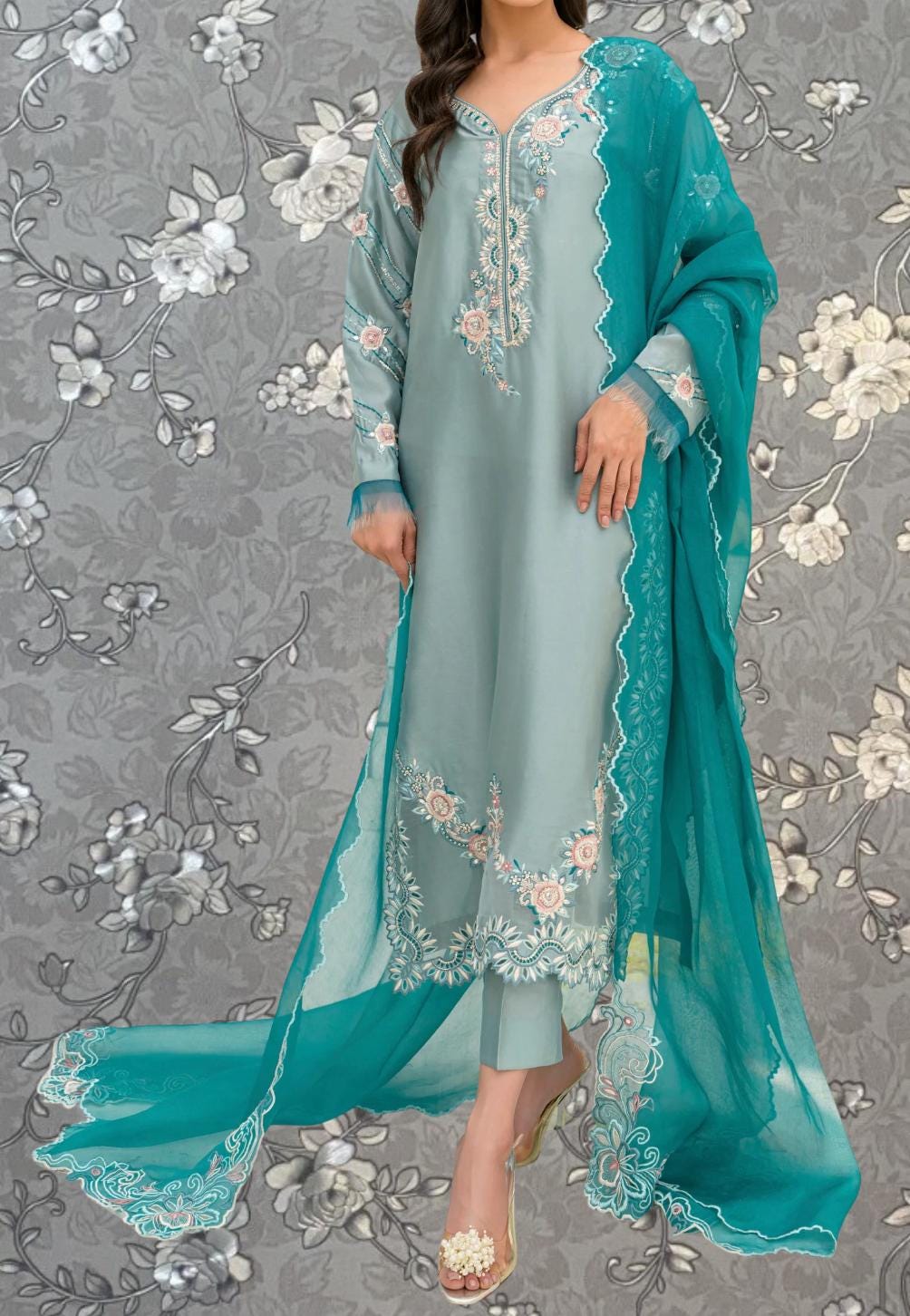 A woman wearing a light blue dress with intricate embroidery and a matching turquoise shawl.