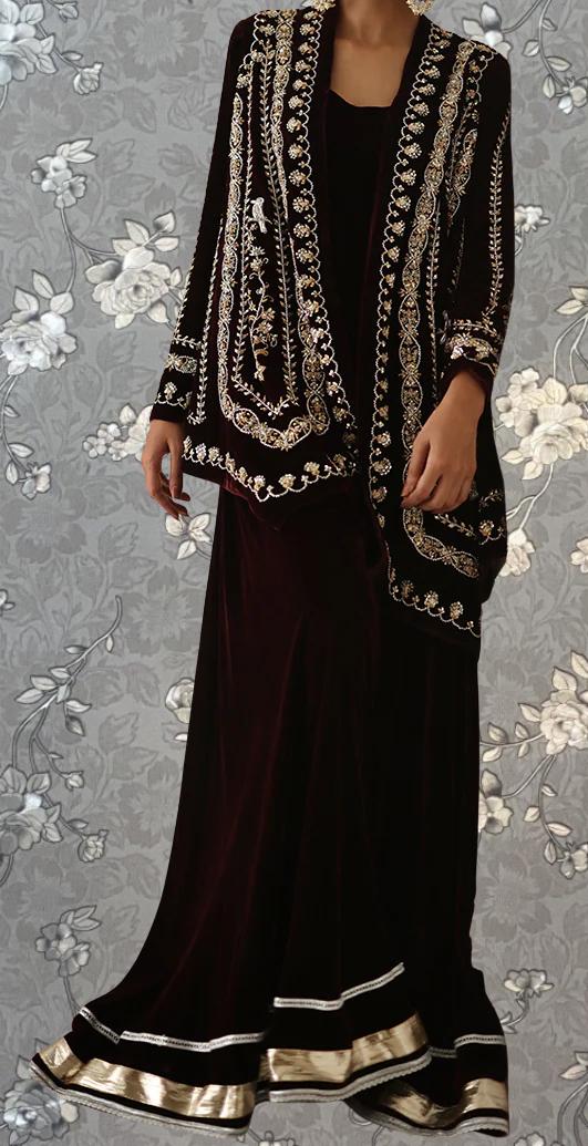 A woman wearing a long, burgundy dress with a black jacket and gold embroidered details.