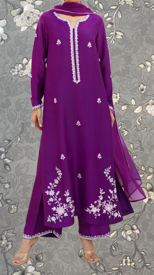 A woman wearing a long purple dress with white floral embroidery on the front.