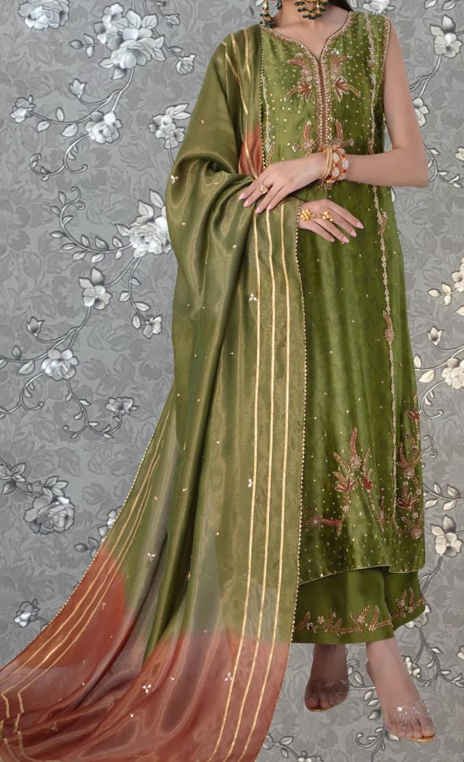 A woman wearing a green and gold dress with a long, flowing skirt and a matching shawl.