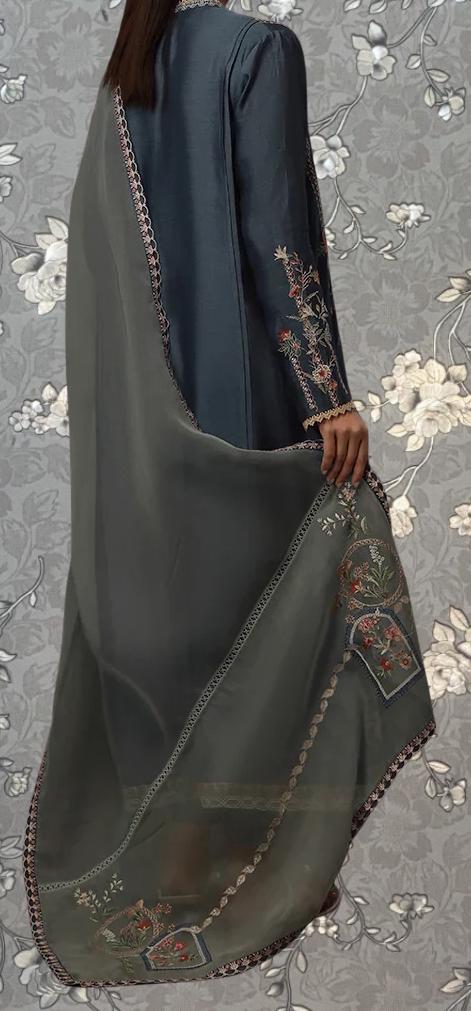 A person wearing a dark blue dress with intricate embroidered designs on the sleeves and a matching gray shawl draped over the shoulders.