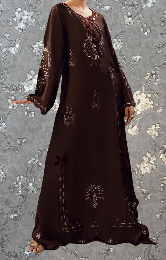 A woman wearing a long, brown dress with intricate embroidery and floral patterns.