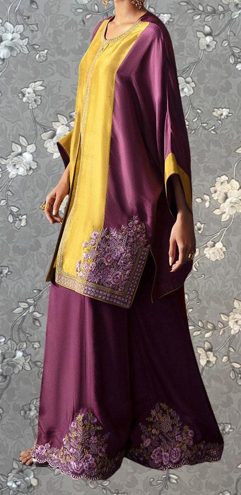 A woman wearing a purple and gold dress with floral embroidery, standing against a gray floral background.