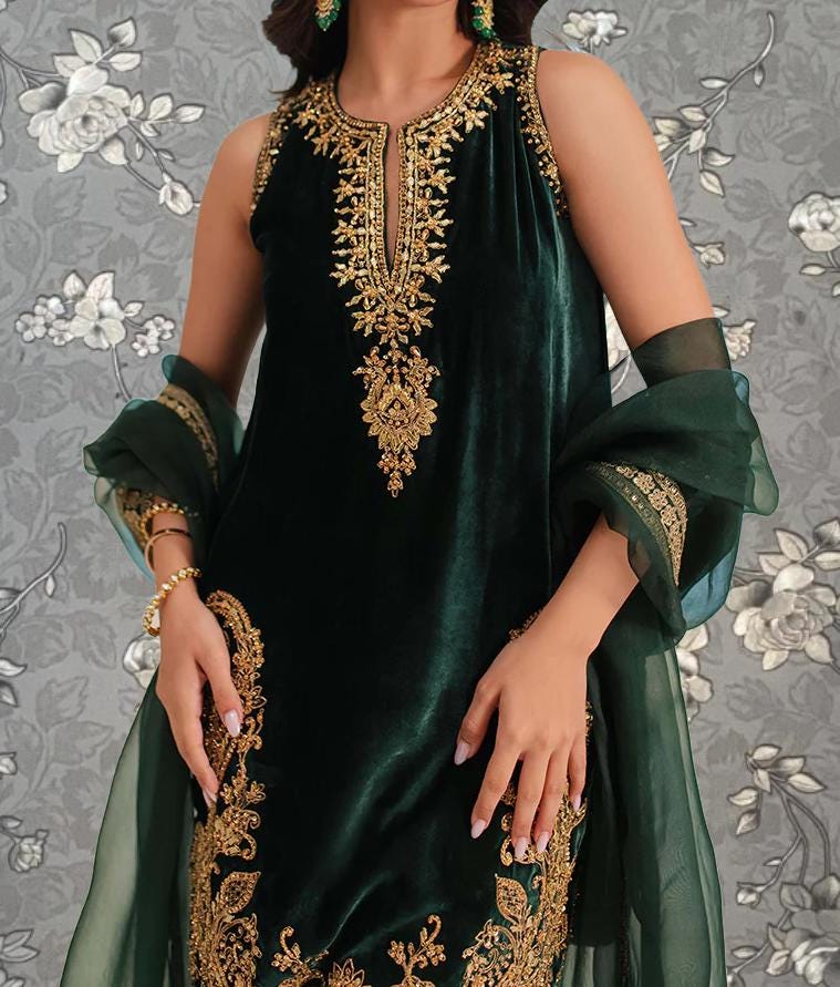 A woman wearing a green velvet dress with gold embroidery and a matching green shawl.