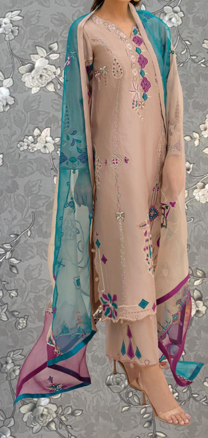 A woman wearing a beige dress with intricate embroidery and a matching turquoise shawl.