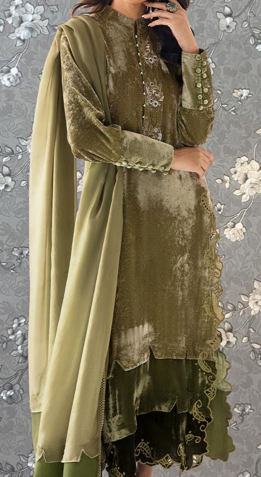 A woman wearing a green and gold dress with a long shawl draped over her shoulders.