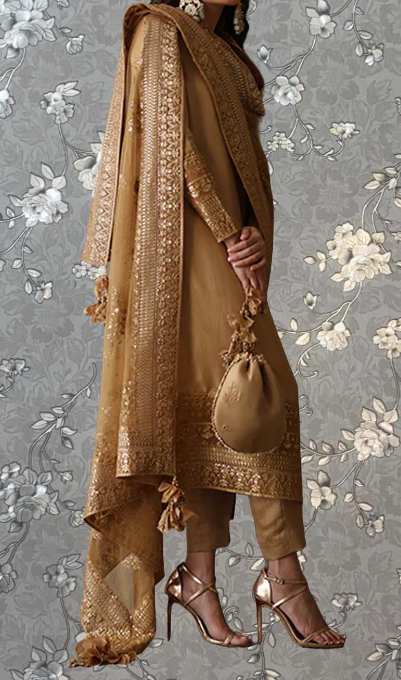 A woman wearing a gold and beige traditional Indian outfit, including a shawl, skirt, and high heels, stands against a gray floral background.