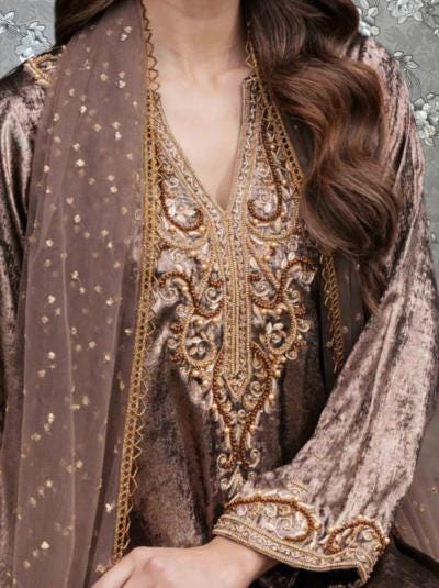 A close-up of a woman wearing a gold and brown embroidered dress with a long, flowing skirt.