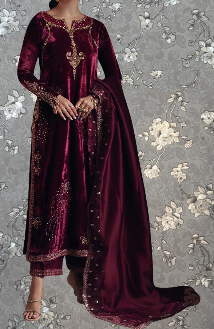 A woman wearing a long, burgundy velvet dress with gold embroidery and a matching shawl.