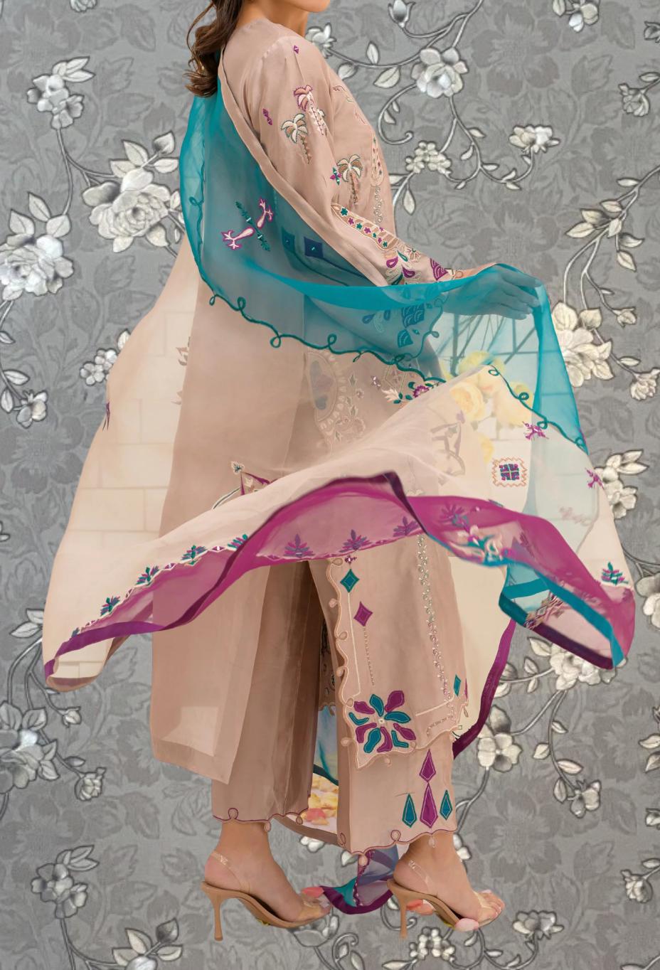 A woman wearing a beige dress with a colorful, flowing skirt and a turquoise shawl is shown against a gray floral background.