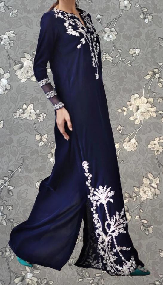 A woman wearing a long navy blue dress with white floral embroidery on the bodice and skirt.