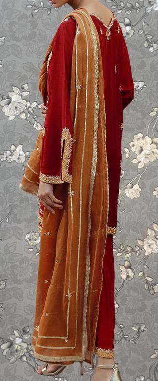 A person wearing a red and gold outfit with a long orange shawl draped over their shoulders.