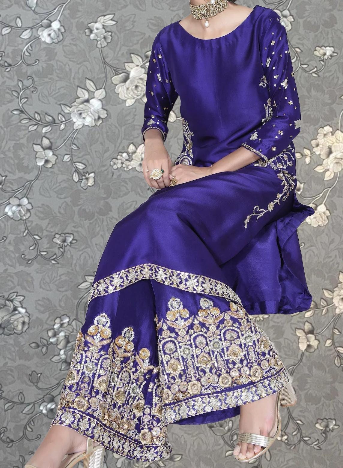 A woman wearing a long, purple dress with gold embroidery and a matching headpiece.