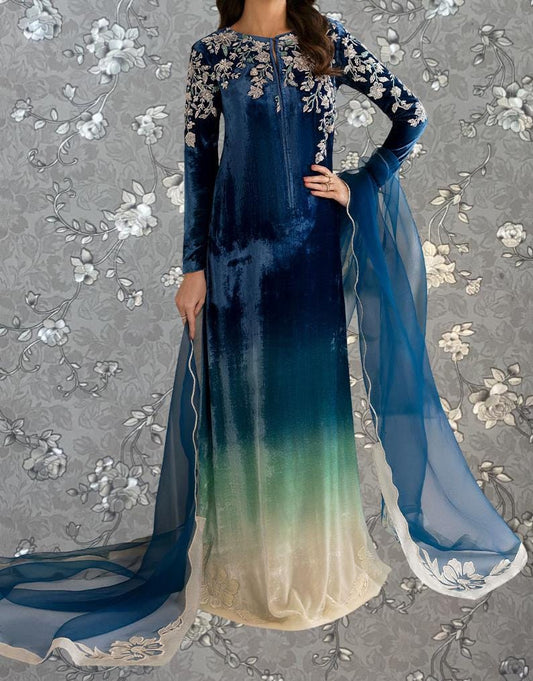 A woman wearing a long blue dress with white floral embroidery and a flowing blue and white sheer skirt.