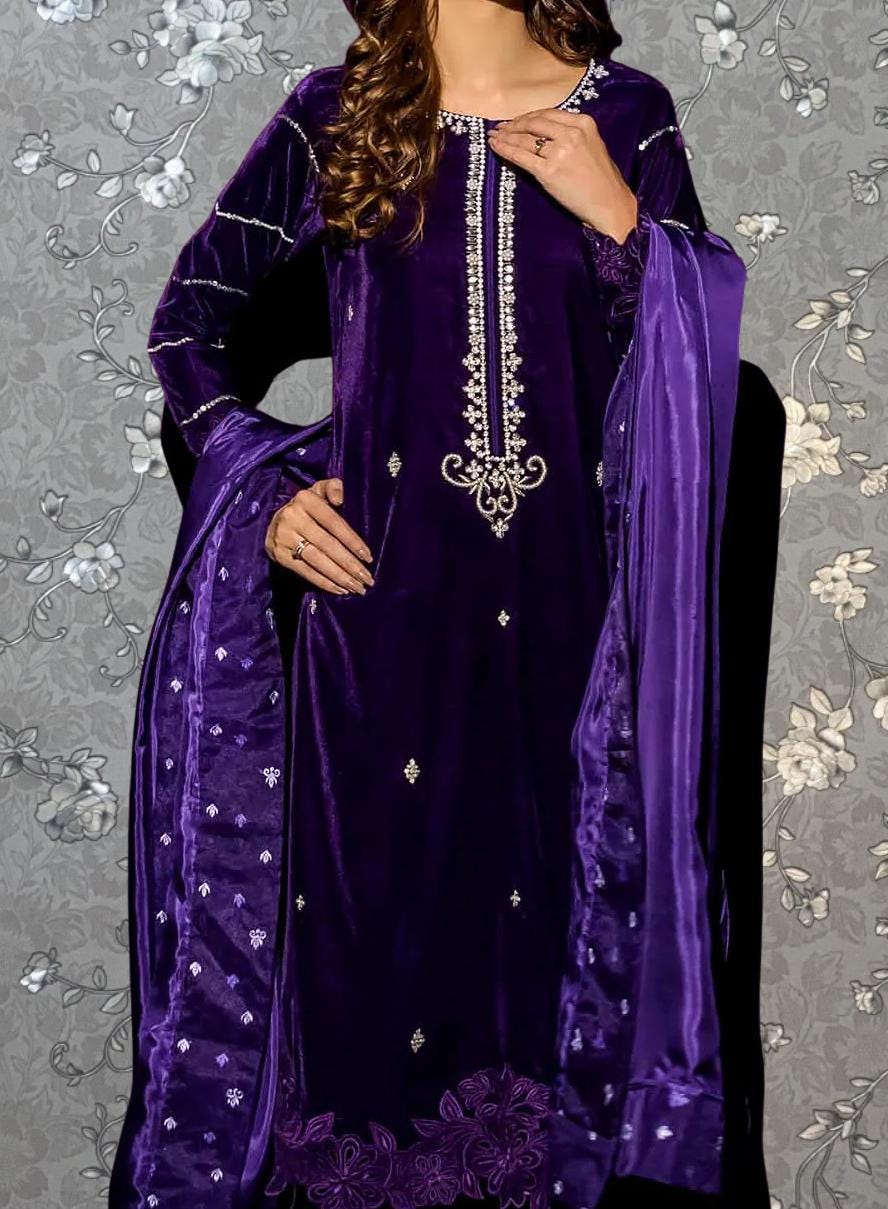 A woman wearing a purple velvet dress with intricate embroidery and a matching purple shawl.