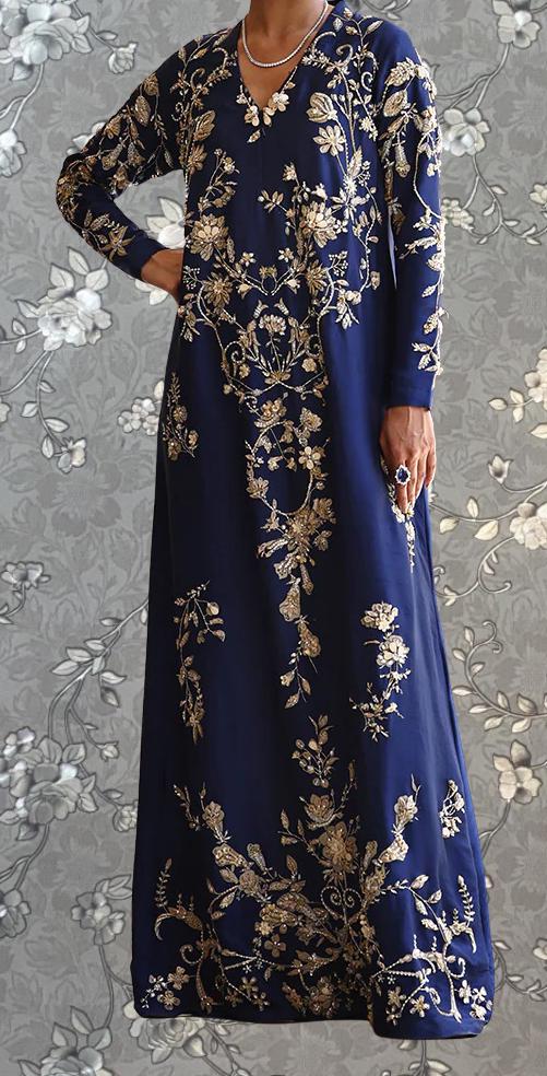 A woman wearing a long, blue dress with gold embroidery stands against a gray floral background.